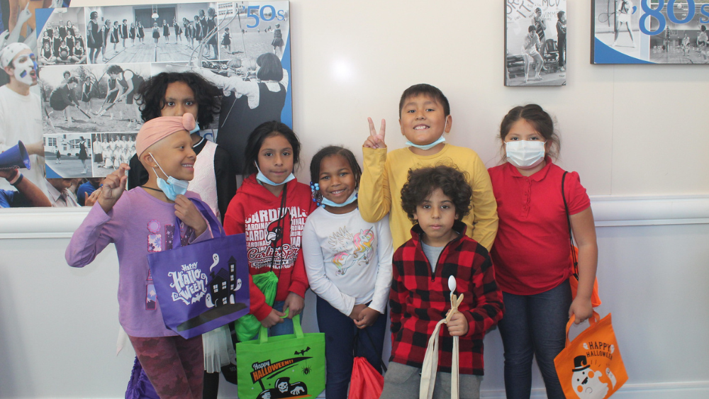 A group of children holding Halloween bags and smiling