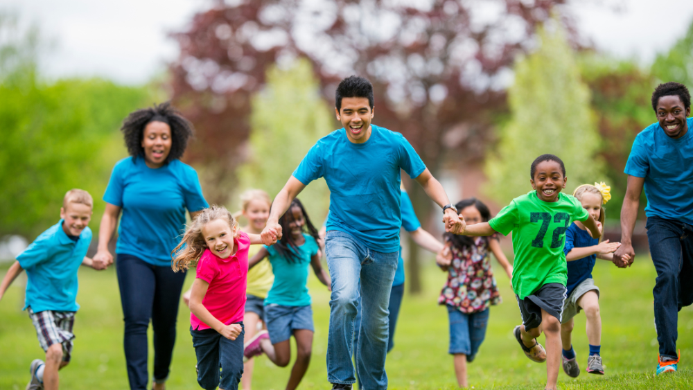 A group of students and adults running and holding hands.