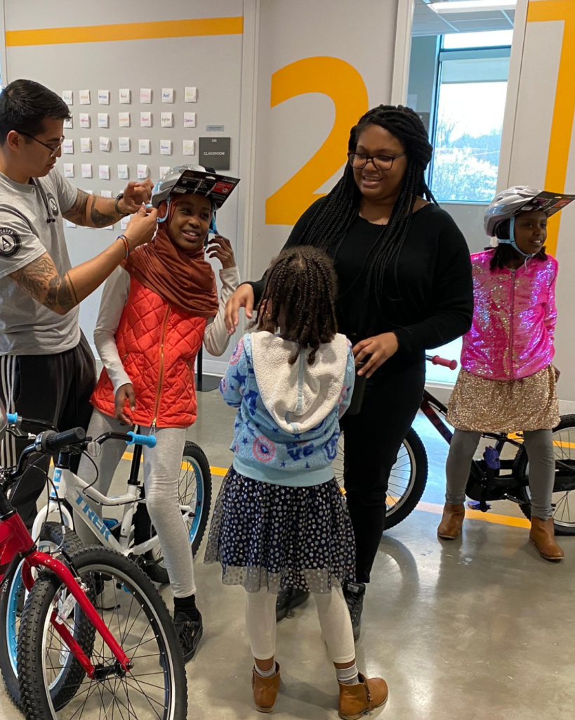 A woman talking to a student as other students get on bikes.