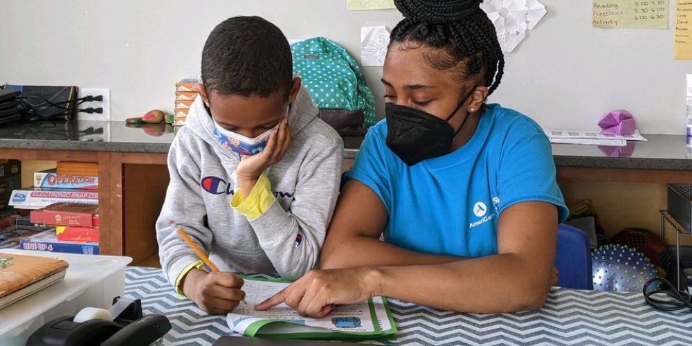 A photo of a young boy and a woman working on homework.