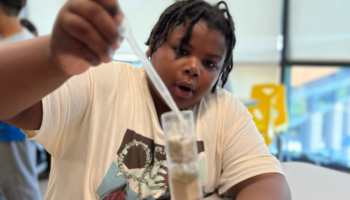 A photo of a student carefully dripping water into an upright water filtration system