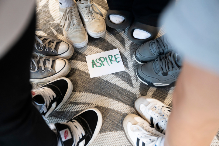 A piece of paper that reads "Aspire" on the ground with feet in a circle around it