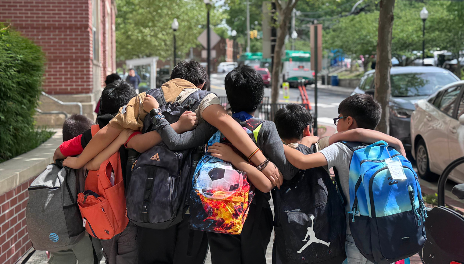 The backs of a group of students walking to Aspire with their arms slung around each other