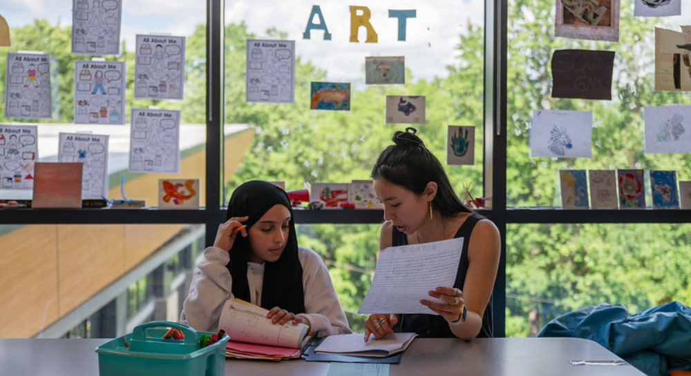 An instructor sitting and working on homework with a student