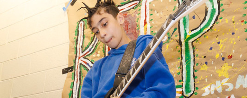Photo of Aspire student playing a guitar