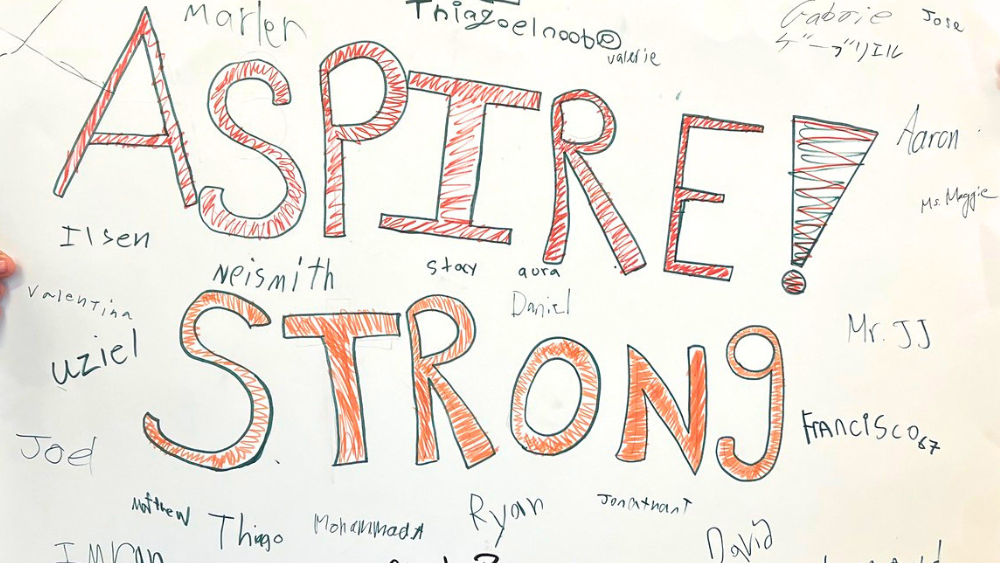 A poster reading "Aspire Strong" with signatures surrounding the words
